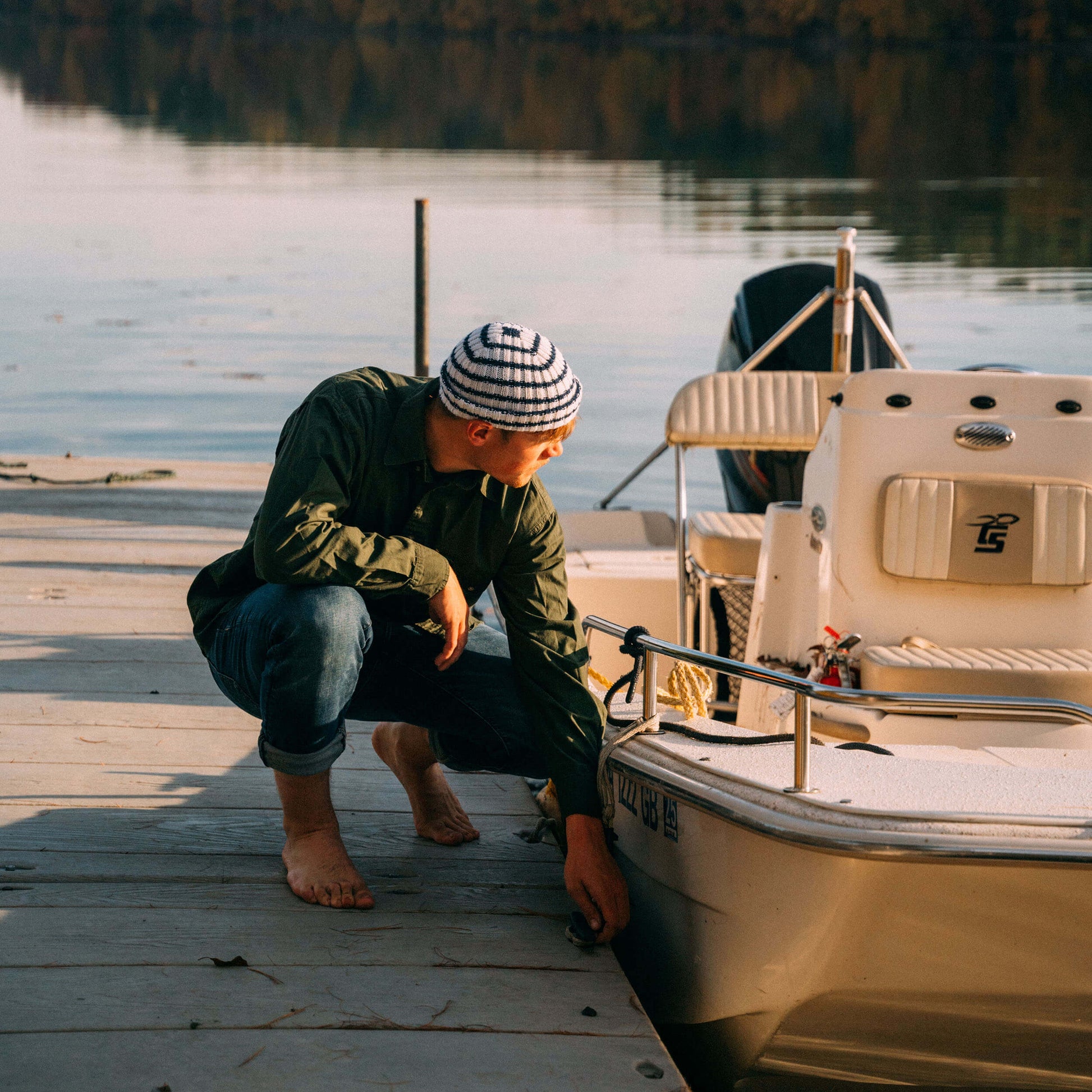 White and navy striped wool beanie, by a boat